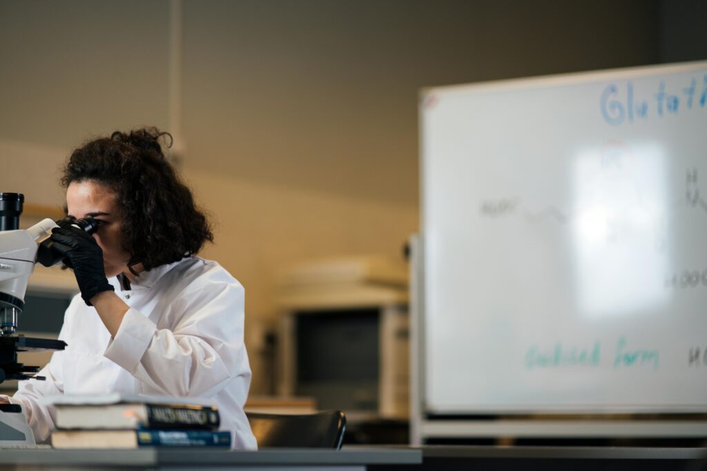 pexels-photo-8851554-8851554 Female scientist examining samples under a microscope in a laboratory setting.