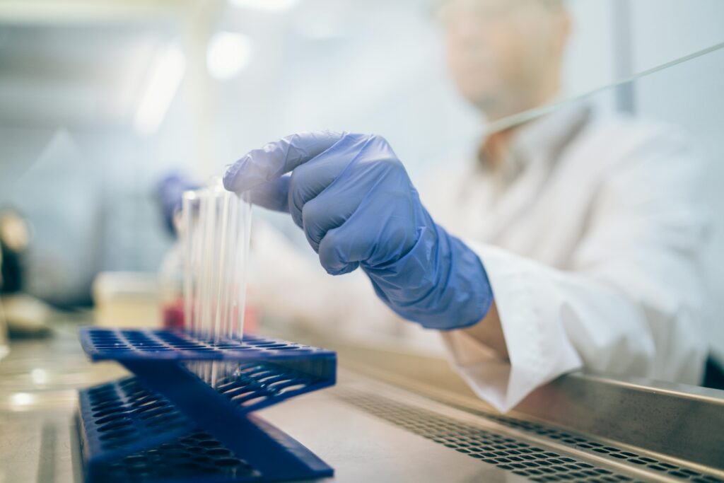 pexels-photo-8863043-8863043 Close-up of a scientist wearing gloves and handling test tubes in a laboratory environment.